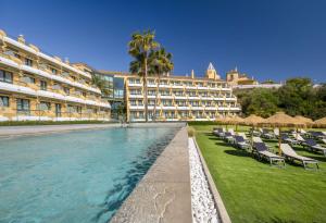 a resort with chairs and a pool and a building at Barceló Jerez Montecastillo & Convention Center in Jerez de la Frontera