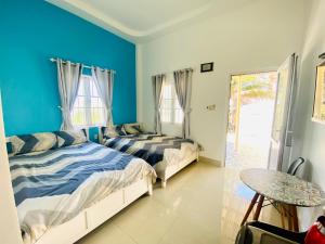 two beds in a room with blue walls and a table at Homestay BONO Mũi Né in Phan Thiet