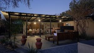 a patio with tables and chairs under a pergola at night at Hambana Lifestyle Lodge in Musina
