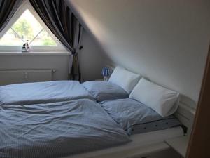 ein unmaskiertes Bett in einem Zimmer mit Fenster in der Unterkunft Ostseespaß in Elmenhorst