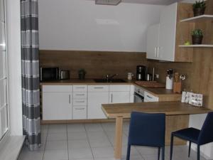 a kitchen with white cabinets and a wooden table and chairs at Ostseespaß in Elmenhorst