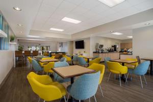 uma cafetaria com mesas e cadeiras e uma cozinha em MainStay Suites Wilmington em Wilmington