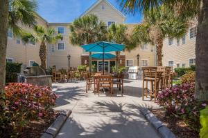 a patio with tables and chairs and a blue umbrella at MainStay Suites Wilmington in Wilmington