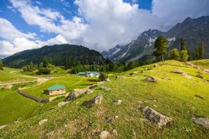 a green field with a house on a hill at Radisson Srinagar in Srinagar