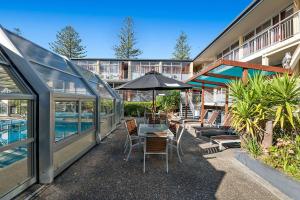 eine Terrasse mit einem Tisch mit Stühlen und einem Sonnenschirm in der Unterkunft Quality Inn Napier in Napier