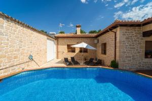 a swimming pool with chairs and an umbrella next to a house at Casa Rural Alvaro in Albares