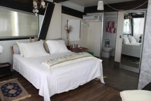 a bedroom with a large white bed and a bathroom at Bungalows de La Casona del Lago in Serranillos Playa