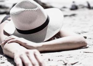 a woman laying on the beach wearing a hat at Club Hotel Anjeliq in Alanya