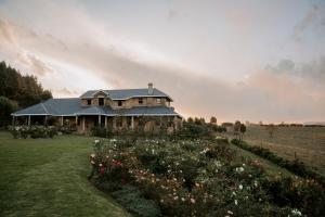 a house in a field with flowers in front of it at Thyme Out Weltevreden Farm in Curryʼs Post