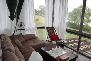a living room with a couch and a large window at Bungalows de La Casona del Lago in Serranillos Playa