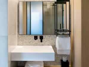 a bathroom with a white sink and a mirror at Mercure Larnaca Beach Resort in Larnaka