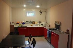 a kitchen with red cabinets and a stove top oven at Skarlett Guest House in Lazarevskoye
