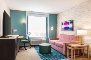 a living room with a pink couch and a desk at Home2 Suites By Hilton Milwaukee West in West Allis