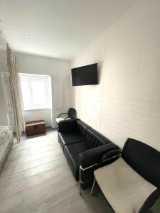 a living room with a black couch and a tv at Stone Rose House in Nazaré