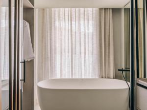 a white bath tub in a bathroom with a window at Mondrian Ibiza in Cala Llonga