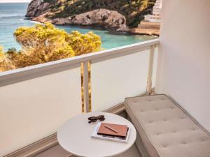 een tafel met een boek en glazen op een balkon bij Mondrian Ibiza in Cala Llonga