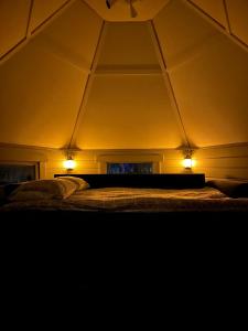 a bed in a room with two lights on it at Camp Caroli Hobbit Hut in Jukkasjärvi