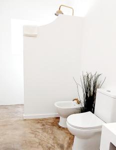 een witte badkamer met een toilet en een plant bij Mileu slowhouse in Veiros