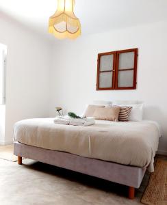 Dormitorio blanco con cama grande y lámpara de araña en Mileu slowhouse, en Veiros