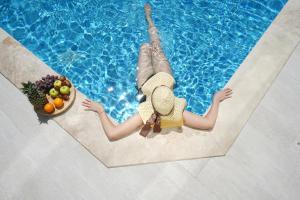 a woman laying in a swimming pool with a bowl of fruit at KAYA APARTMENTS in Kalkan
