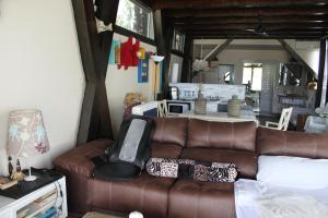 a living room with a brown couch and a kitchen at Bungalows de La Casona del Lago in Serranillos Playa +8 photos
