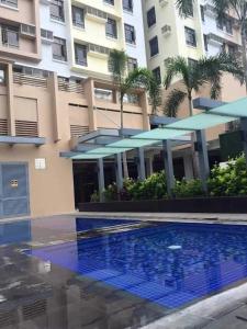 a hotel with a swimming pool in front of a building at Relaxing 2-Bed Apartment in Mandaluyong in Manila