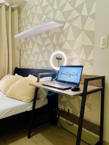 a laptop computer sitting on a desk next to a bed at Relaxing 2-Bed Apartment in Mandaluyong in Manila
