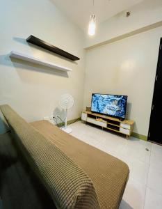 a living room with a bed and a flat screen tv at Relaxing 2-Bed Apartment in Mandaluyong in Manila