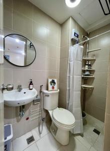 a bathroom with a toilet and a sink and a mirror at Relaxing 2-Bed Apartment in Mandaluyong in Manila