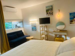 1 dormitorio con cama, sofá y TV en Studio Fresh&Cosy Trois-Ilets - 3 étoiles-Hotel Carayou, en Les Trois-Îlets