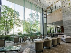 a lobby with chairs and tables and large windows at The Strings Hotel Nagoya in Nagoya