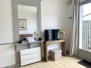 a room with a desk with a tv and a mirror at LA JOLIE BRISE APPARTEMENT DANS RÉSIDENCE AVEC PISCINE in La Flotte