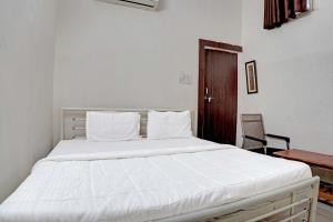 a white bed in a room with a wooden door at New Narayan Palace in Bhopal