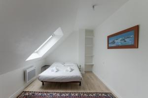 Cette chambre blanche dispose d'un lit et d'une photo murale. dans l'établissement TY PRAT - Jolie maison neuve proche mer, à Landunvez