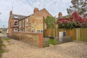 a brick house with a wooden fence in front of it at Heacham Hidey Hole in Heacham