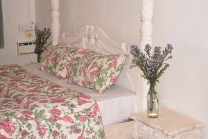 1 dormitorio con 1 cama con un jarrón de flores sobre una mesa en Casa Happy Dervish, 2mins away from the beach, en Anjuna