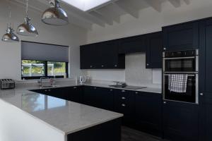 uma cozinha com armários pretos e bancadas brancas em Otters Cove, Middleton Hall Estate em Belford