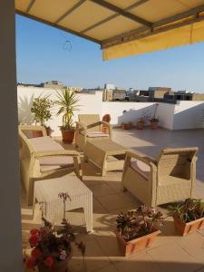 une terrasse avec des chaises et des tables en osier et des plantes en pot dans l'établissement Appartement de luxe près de la mer, à Nabeul