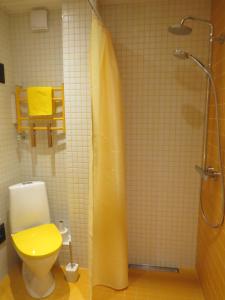 y baño con ducha, aseo y cortina de ducha amarilla. en Perepuhkus Apartment, en Pärnu