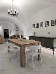 a dining room with a wooden table and white chairs at LianHome b&b "Volte" in Lucera