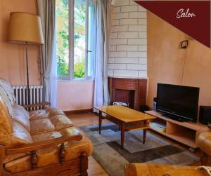 salon z kanapą i telewizorem w obiekcie VILLA ANNEE 30 Rénovée ,Terrasse et Jardin w mieście Souillac