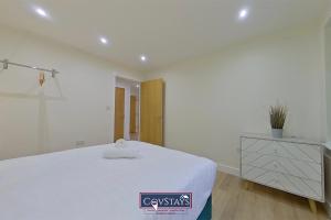 a white bedroom with a large bed and a dresser at Beauchamp House - Apartment in Coventry City Centre, Sleeps 4, Free secure parking, by CovStays in Coventry