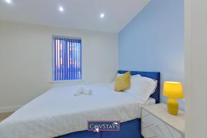 1 dormitorio con 1 cama blanca grande con lámpara amarilla en Beauchamp House - Apartment in Coventry City Centre, Sleeps 4, Free secure parking, by CovStays, en Coventry