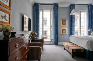 a bedroom with a bed and a dresser and windows at Haymarket Hotel, Firmdale Hotels in London