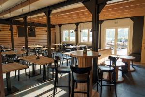 a restaurant with wooden tables and chairs and windows at Penzion Racek in Tuchlovice
