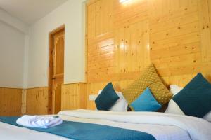 a bedroom with a bed with blue and white pillows at Hotel Neelgiri - Manali Diaries in Manāli
