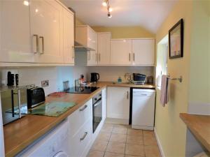 a kitchen with white cabinets and white appliances at 1 Orchard Cottages in West Runton