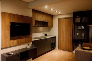 a kitchen with a sink and a tv in a room at Studio contemporâneo no Parque Una com garagem in Pelotas