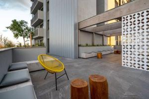 a yellow chair and two wooden stools on a building at Studio contemporâneo no Parque Una com garagem in Pelotas