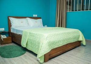 1 dormitorio con 1 cama grande con manta verde en Jackie Grand Hotel, en Cape Coast